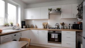 a kitchen with white cabinets and a sink and a table at Boehring Apartments in Dötlingen