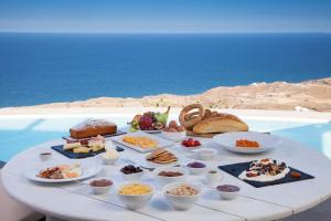 una tavola con cibo sopra con l'oceano sullo sfondo di Dome Santorini Resort a Imerovigli Altre 31 foto