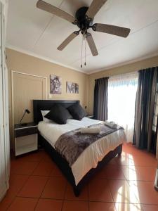 a bedroom with a large bed with a ceiling fan at Kingfisher Hideaway in Nelspruit
