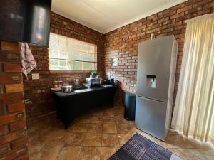 a kitchen with a refrigerator and a brick wall at Kingfisher Hideaway in Nelspruit +16 photos