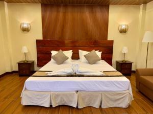 a bedroom with a large bed with two white towels at Balai Amihan Bed & Breakfast in Talisay
