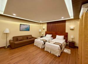 a hotel room with two beds and a couch at Balai Amihan Bed & Breakfast in Talisay +6 photos