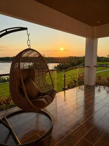 a hanging chair on a porch with the sunset at Balai Amihan Bed & Breakfast in Talisay