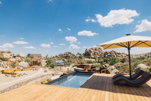 a patio with an umbrella and a swimming pool at Mod West Ranch: 5-acre Boulder Playground in Pioneertown