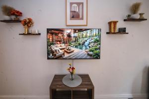 a tv on a wall with a picture of a living room at Sunny Haven House in Jersey City