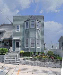 a gray house with a staircase in front of it at Sunny Haven House in Jersey City