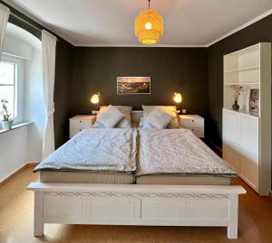a bedroom with a large white bed with green walls at Ferienwohnung Haus Kreutz in Bruttig-Fankel