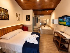 a bedroom with a bed and a television and a tub at Pousada Charmosa Lua Nova Pipa - Chales com Jacuzzi e Hidro in Pipa +32 photos