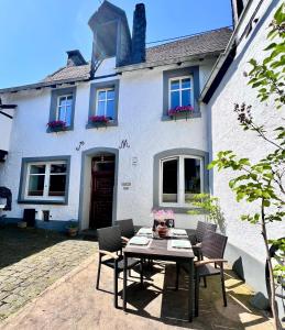 a table and chairs in front of a white house at Ferienwohnung Haus Kreutz in Bruttig-Fankel