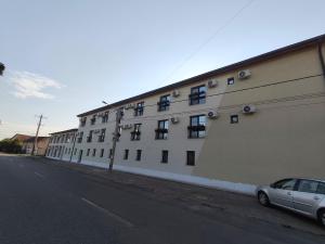 a white building with a car parked in front of it at Hotel Amstar Simeria in Simeria