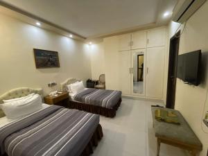a hotel room with two beds and a television at New Panoramic Hotel in Lahore