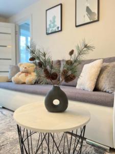 a vase with pine cones on a table in front of a couch at New Modern Apartments in the City Center in Narva