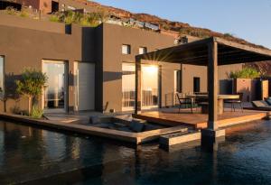 a house on the water with a wooden dock at Anzo Villas in Oia