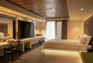 a bedroom with a bed and a desk with a television at Anzo Villas in Oia +147 photos