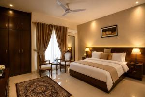 a hotel room with a large bed and a chair at Elite Creek Clifton in Karachi
