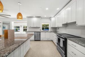 a kitchen with white cabinets and granite counter tops at Backyard Oasis with Pool & Games in West Palm Beach
