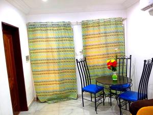 a dining room with a table and chairs and curtains at Ouedraogo Property Management in Ouagadougou +4 photos