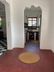 an empty room with a kitchen and aoyer with red floor at Meama Paje Guesthouse in Paje