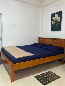 a bedroom with a bed with blue sheets and a picture at Devil mountain villa- kalupahana in Etimole