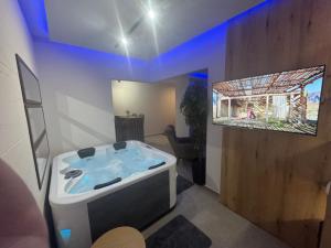 a bathroom with a tub with a tv on the wall at Omnia Lux Apartman 4C in Šabac