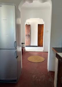 a kitchen with a refrigerator and a hallway with two doors at Meama Paje Guesthouse in Paje