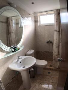a bathroom with a sink and a toilet and a mirror at Glyfa Beach Hotel in Vartholomio