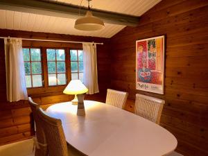 a dining room with a table with chairs and a lamp at Cozy and authentic log house in Dronningmølle +18 photos