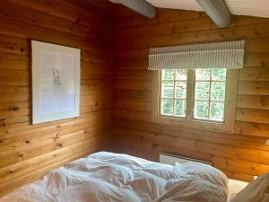 a bedroom with a bed in a wooden room at Cozy and authentic log house in Dronningmølle