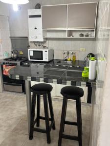 a kitchen with a counter and two bar stools at Depto hube in La Banda