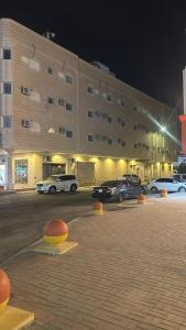a large building with cars parked in a parking lot at فيو بارك للاجنحة الفندقية in Al Kharj