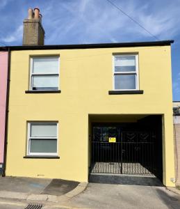 a yellow building with a garage at Buttercup Victorian House for 6 in St. Leonards