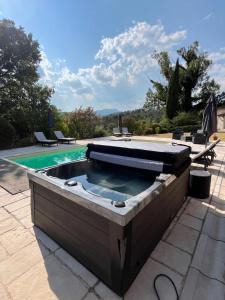 a hot tub on a patio next to a swimming pool at L'Échappée Cévenole in Gagnières