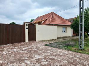 a house with a fence and a brick driveway at BOTANIKA apartmanok Zsálya és Rozmaring in Baja