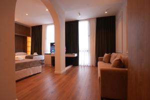a living room with a couch and a bed and a television at Eden Center Rooms in Durrës