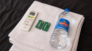 a bottle of water and a remote control on a towel at Shree Vaishnav Yatri Grah Near Mahakaleshwar Temple in Ujjain