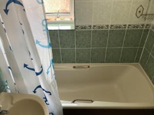 a bathroom with a tub and a shower curtain at Harman Suites 1 & 2 in Leeds