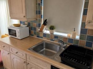 a kitchen counter with a sink and a microwave at Harman Suites 1 & 2 in Leeds