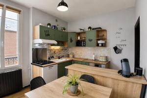 a kitchen with green cabinets and a wooden table at Gîte du Pré Nattier - Gisors centre in Gisors +17 photos