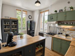 a kitchen with green cabinets and a wooden counter top at Gîte du Pré Nattier - Gisors centre in Gisors