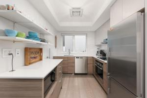 a kitchen with a stainless steel refrigerator and wooden cabinets at Elite Townhouse at the Shipyaards in North Vancouver