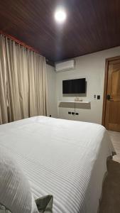 a bedroom with a large white bed and a tv at Altura525 hotel in Jarabacoa