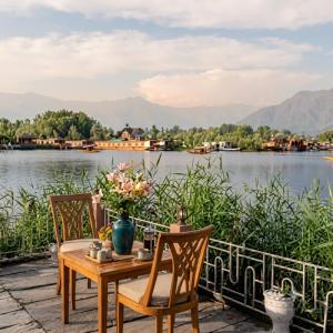 a table and chairs with a view of a lake at Kashmir View group of Houseboat in Srinagar