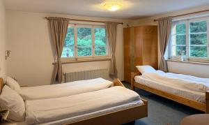 two beds in a room with two windows at Hotel Alp Sur in Mühlen