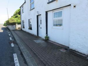 a white building with a door next to a street at The Coach House Self Catering Apartments in Glenariff