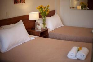 a hotel room with two beds and a vase with flowers at El Angolo Chosica in Nicolas de Pierola