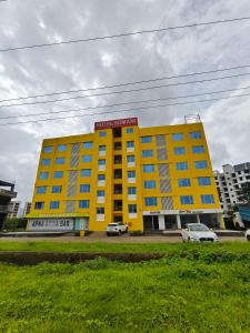 a yellow building with cars parked in front of it at The Moon Hotel Panvel in Āpta