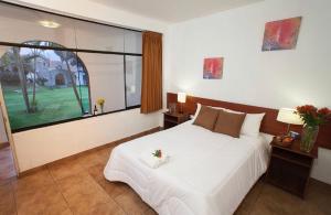 a bedroom with a large bed and a large window at El Angolo Chosica in Nicolas de Pierola