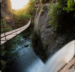 a bridge over a river next to a waterfall at Aire de sierra in Monachil