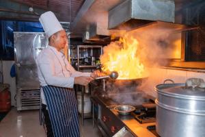a chef cooking on a stove in a kitchen at Hotel Royal Inn in Nawākot
