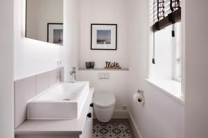 a white bathroom with a sink and a toilet at Reethaus Nordgold in Oldsum